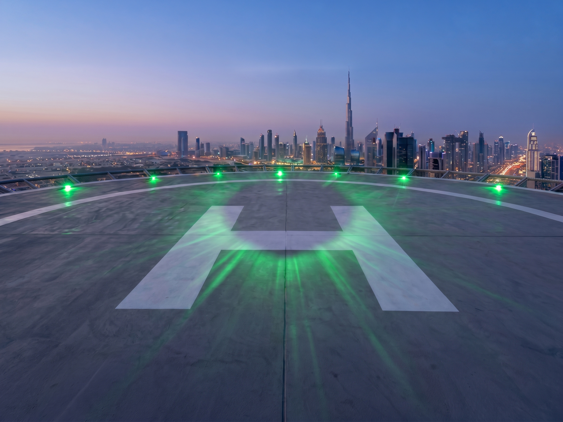 Illuminated rooftop helipad with green perimeter lights over the Dubai skyline